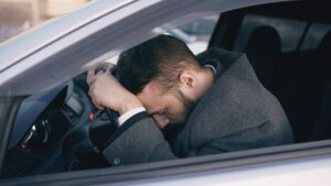 man resting on car steering wheel
